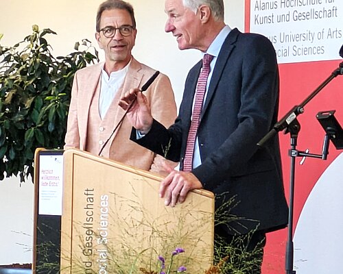 Das Bild zeigt zwei Männer hinter einem Rednerpult.