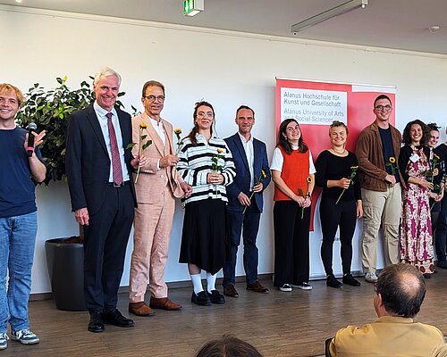 Das Bild zeigt eine Gruppe Menschen auf einer Bühne.