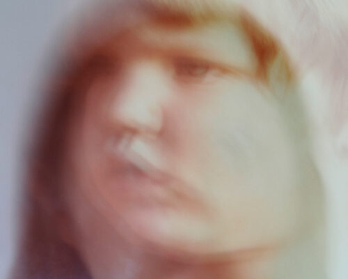 Abstraktes, verschwommenes Porträt eines Gesichts mit weichen Pastellfarben, bei dem die Konturen von Augen, Nase und Mund nur schemenhaft zu erkennen sind.