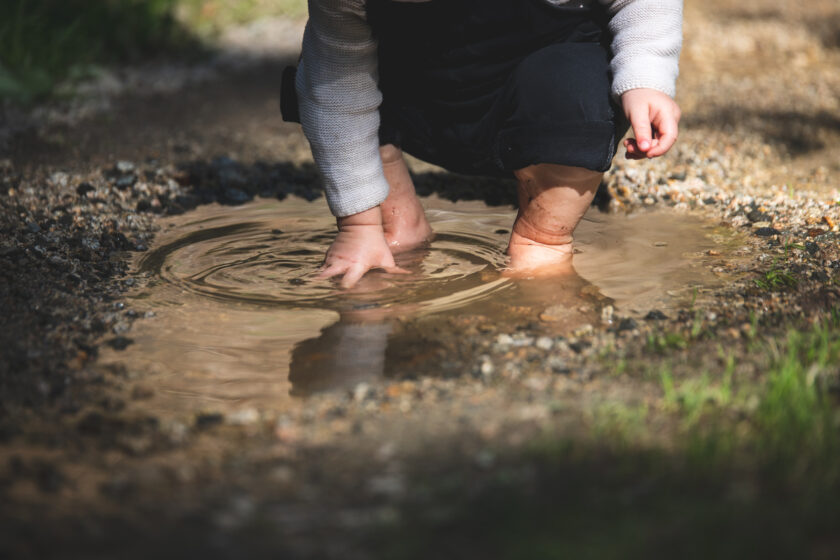 Kind Barfuss in Pfütze mit Spiegelung