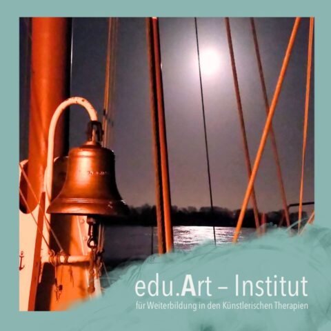 Nachtaufnahme von einem Segelschiff: Im Vordergrund hängt eine bronzefarbene Schiffsglocke an einem Mast, dahinter verlaufen mehrere beleuchtete Taue nach oben.