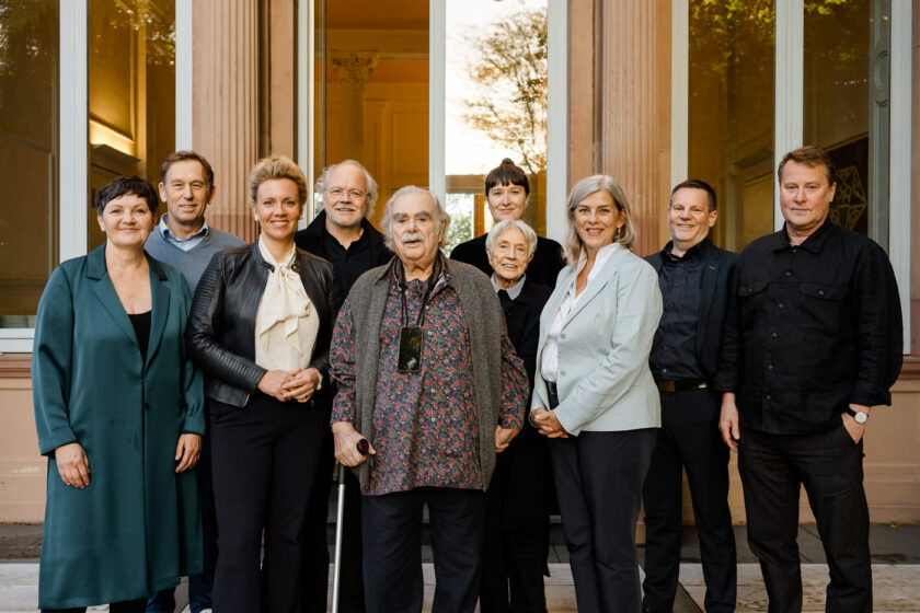 Sie sehen eine Gruppe Menschen vor einem Gebäude