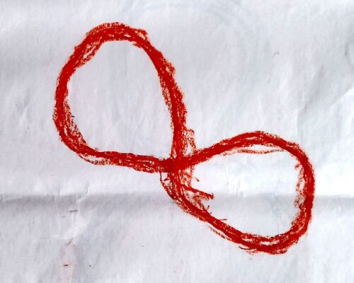 Ein grob mit rotem Wachsmalstift gezeichneter, liegender Achter auf weißem, leicht zerknittertem Papier.