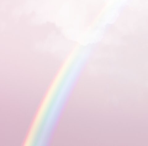 Weicher, pastellfarbener Regenbogen vor einem zart rosa Himmel mit leichten Wolken.