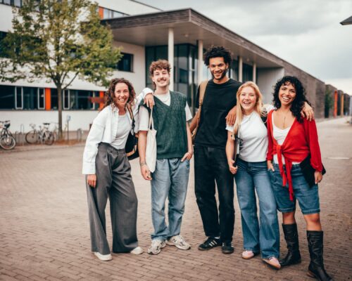 Das Bild zeigt eine Gruppe junger Menschen vor einem Gebäude.