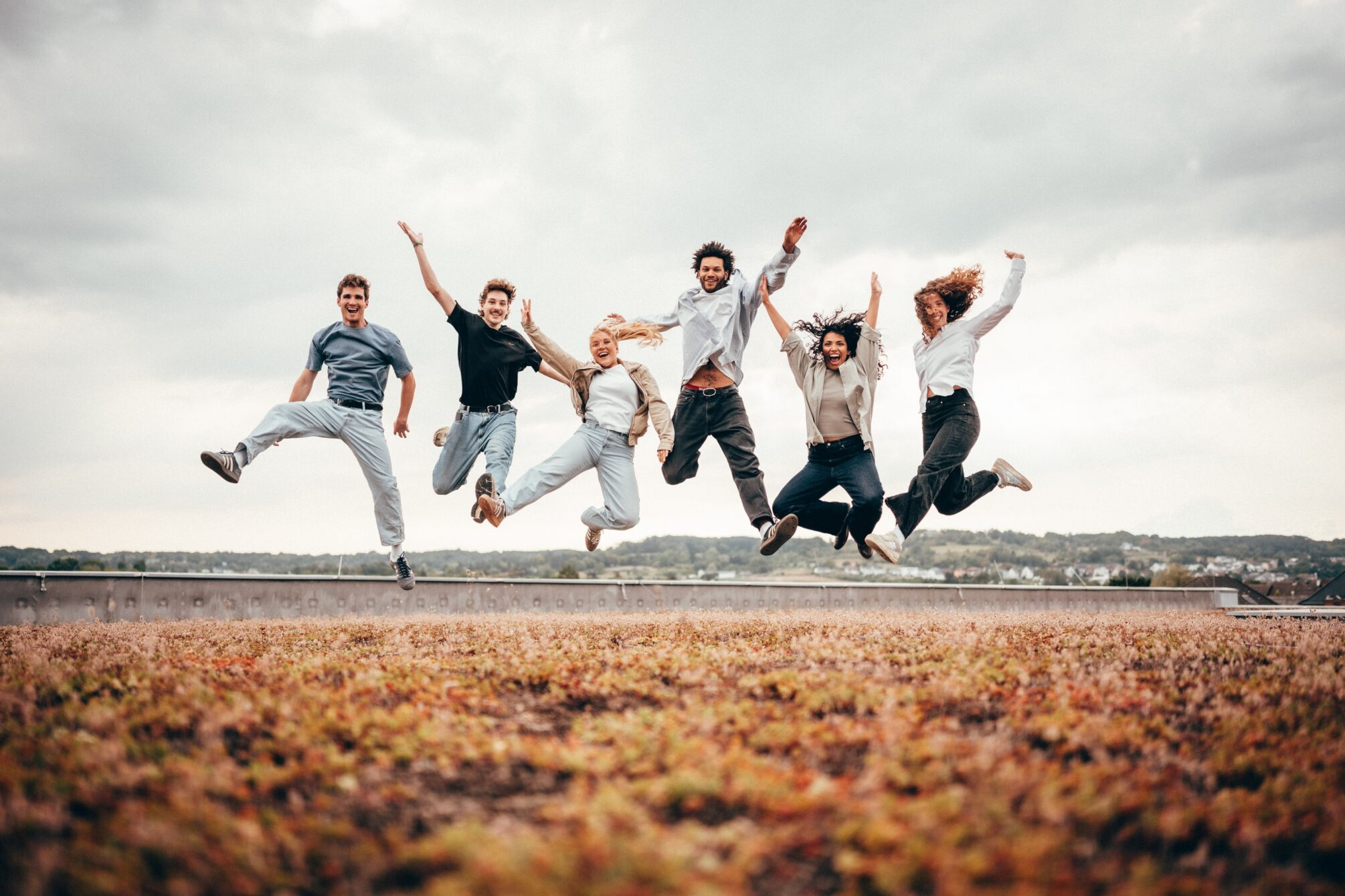 Das Bild zeigt eine Gruppe junge Menschen, die in die Luft hüpft.