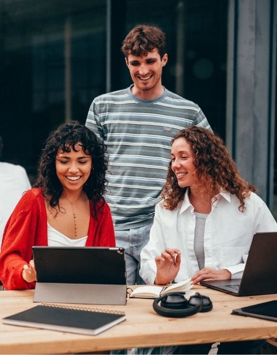 Das Bild zeigt eine Gruppe junger Menschen vor einem Laptop.