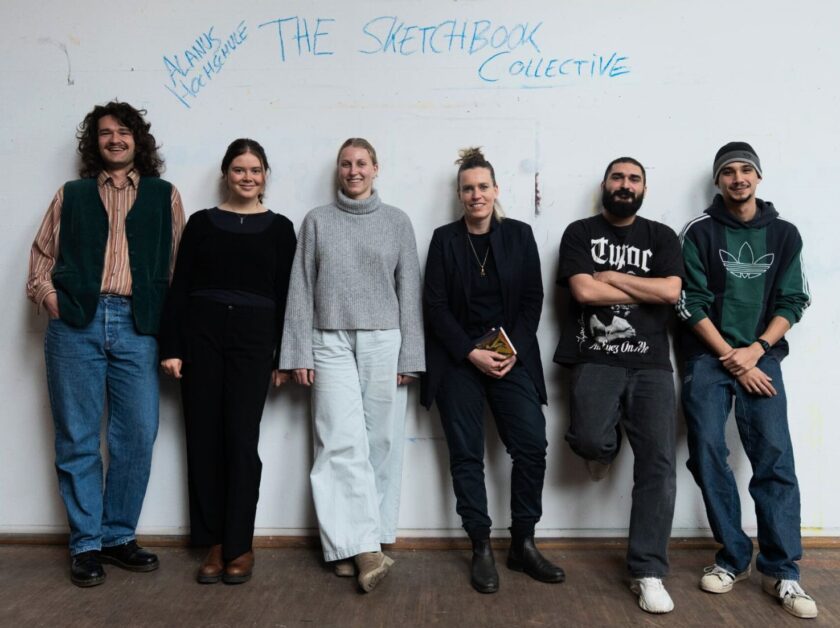 Sechs junge Erwachsene stehen lächelnd nebeneinander vor einer weißen Wand, auf der mit blauer Schrift „THE SKETCHBOOK COLLECTIVE“ und „Akane Hochschule“ geschr