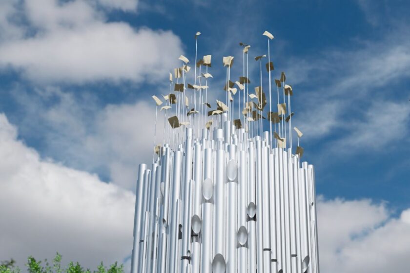 Moderne Skulptur aus vielen senkrechten silbernen Röhren, aus deren Spitzen dünne Stäbe mit kleinen goldenen Metallplättchen ragen, vor blauem Himmel mit weißen