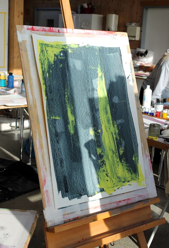 Staffelei in einem hellen Atelier mit einem abstrakten Gemälde, das aus einer großen dunkelblauen Fläche mit leuchtend gelben, vertikalen Pinselstrichen besteht