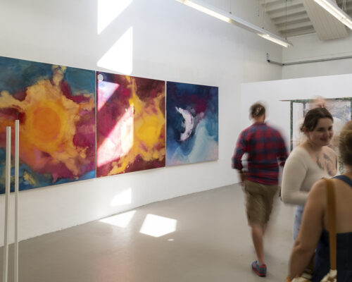 Innenaufnahme einer hellen Galerie mit vier großen, farbintensiven abstrakten Gemälden an der linken Wand, die an kosmische Nebel mit Sonne und Mond erinnern. M