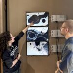 Zwischen Seidenstraße und Gegenwartskunst 9 Zwei Personen stehen vor einer Wandinstallation aus drei übereinander montierten Bildschirmen mit abstrakten, an Planeten und Krater erinnernden Schwarz-Weiß-Mu